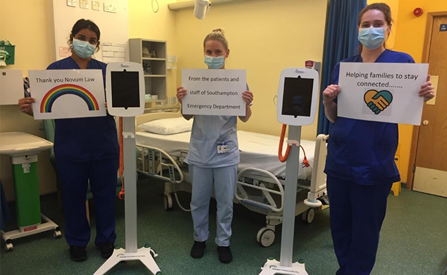 ICU Staff hold signs to thank Novum Law for iPad Cart donation
